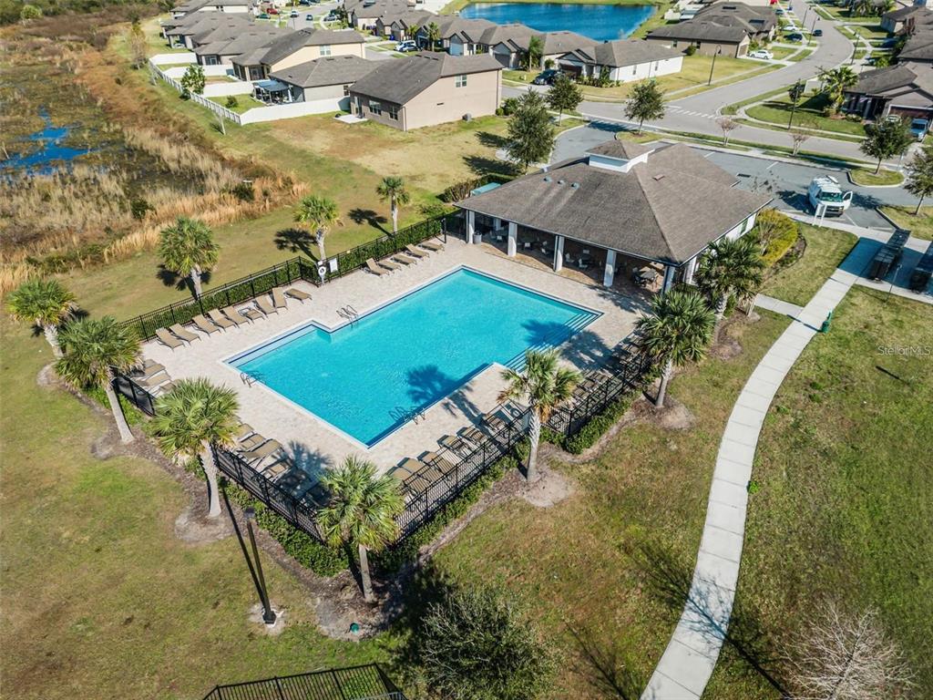 An aerial view shows a community swimming pool and clubhouse surrounded by a fenced deck — 3617 VEGA CREEK DRIVE, ST CLOUD, FL