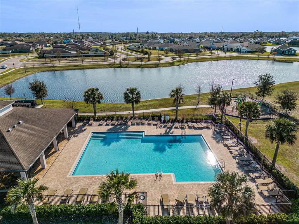 An aerial view of a community swimming pool with lounge chairs and a nearby lake — 3617 VEGA CREEK DRIVE, ST CLOUD, FL