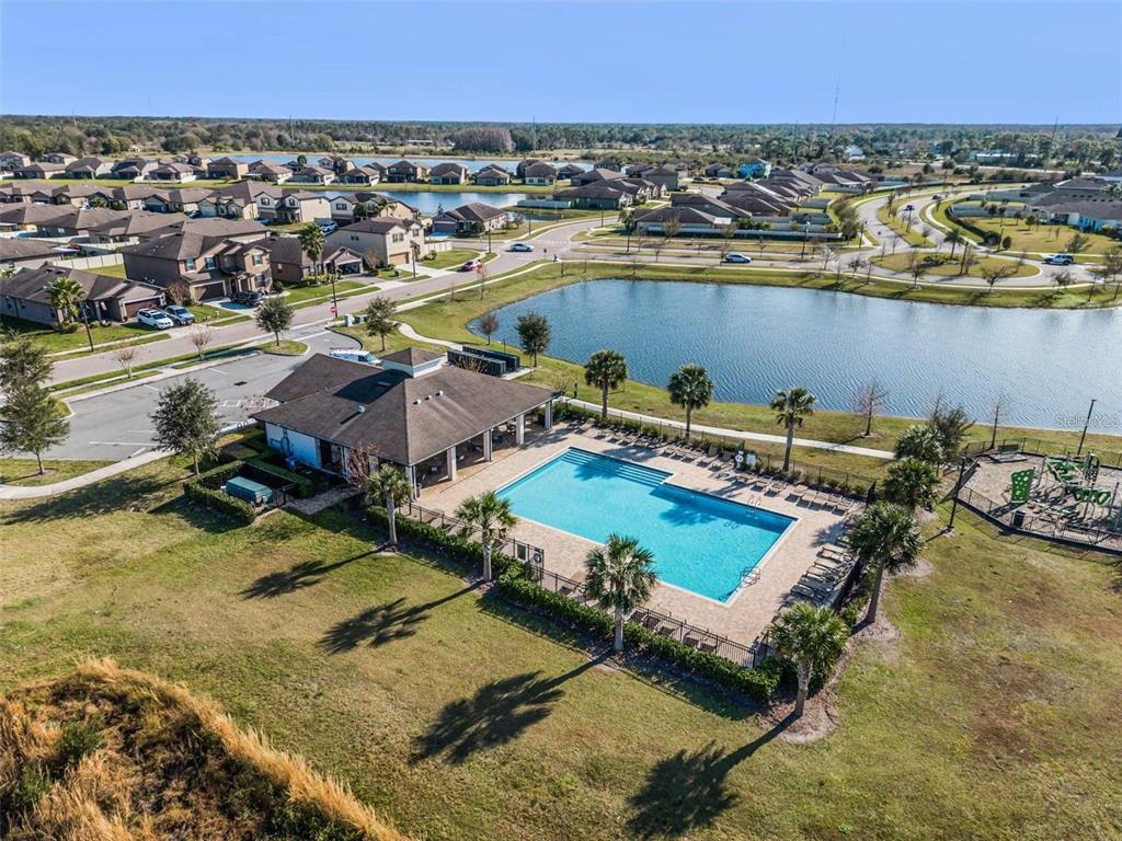 An aerial view shows a community swimming pool and clubhouse next to a large pond — 3617 VEGA CREEK DRIVE, ST CLOUD, FL