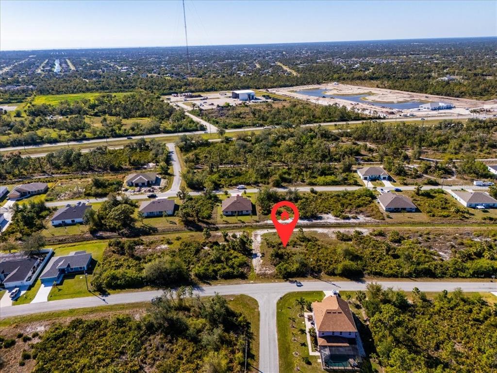 An aerial view shows a vacant, brush-covered residential lot marked by a red location pin — 9235 WALDREP STREET, PORT CHARLOTTE, FL