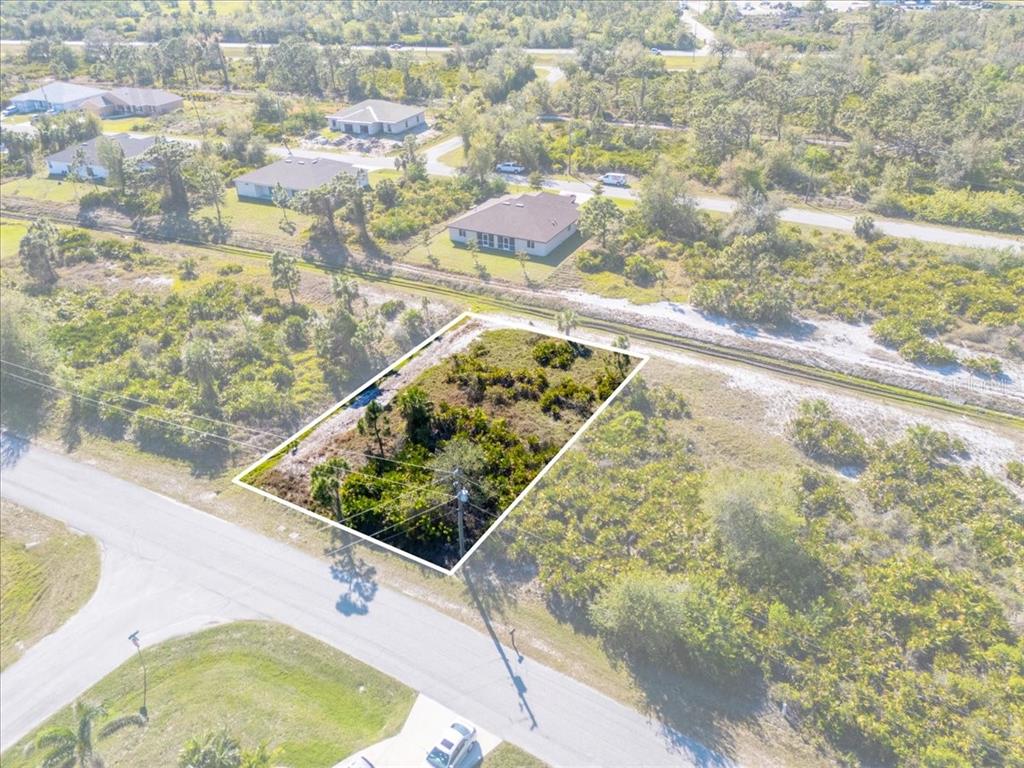 An aerial view shows a rectangular vacant lot surrounded by vegetation and nearby residential houses — 9235 WALDREP STREET, PORT CHARLOTTE, FL