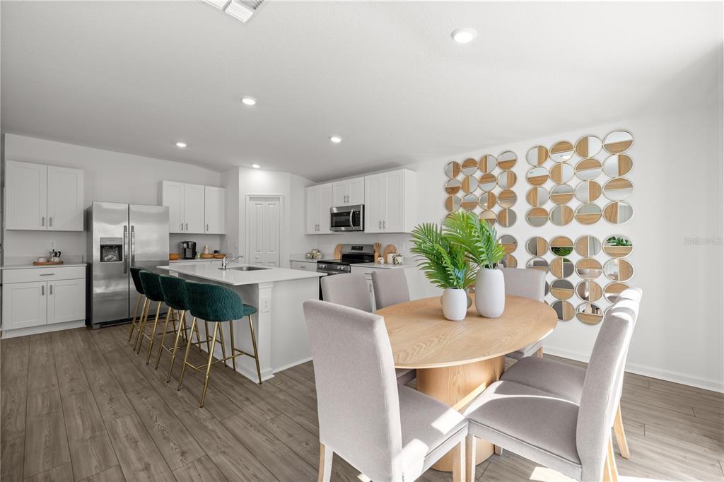 A modern kitchen and dining area with white cabinets, a central island, and wood flooring — 4822 NW 16TH STREET, OCALA, FL