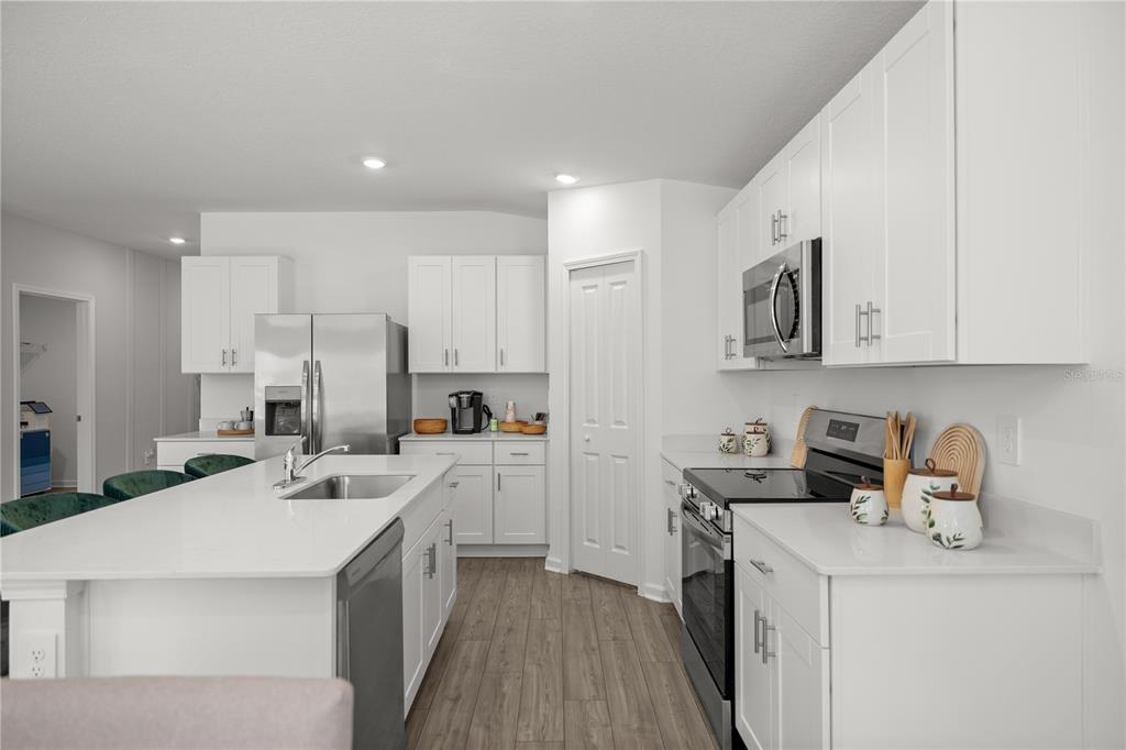 A modern kitchen features white cabinetry, stainless steel appliances, a center island, and wood-look flooring — 4822 NW 16TH STREET, OCALA, FL