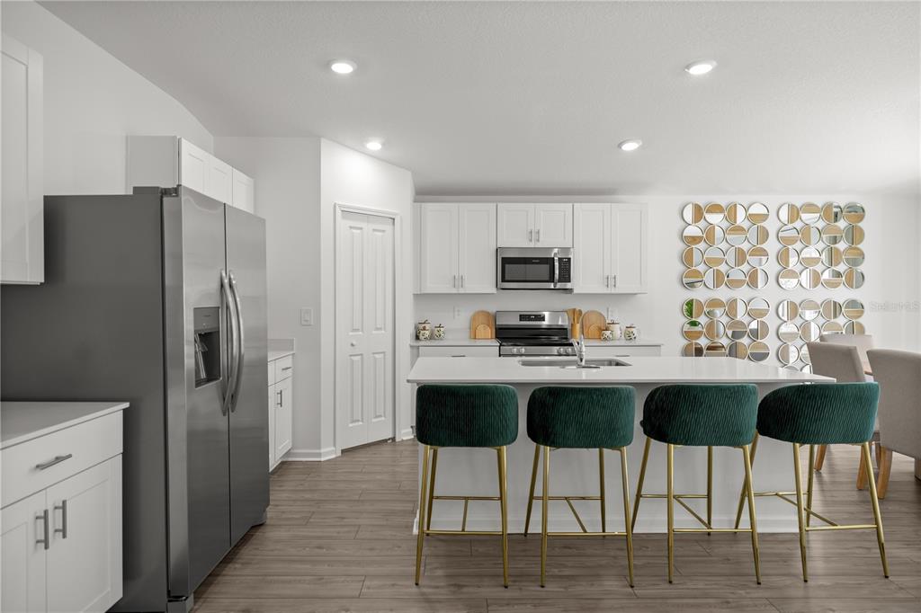 A modern kitchen features white cabinetry, stainless steel appliances, a center island, and green stools — 4822 NW 16TH STREET, OCALA, FL