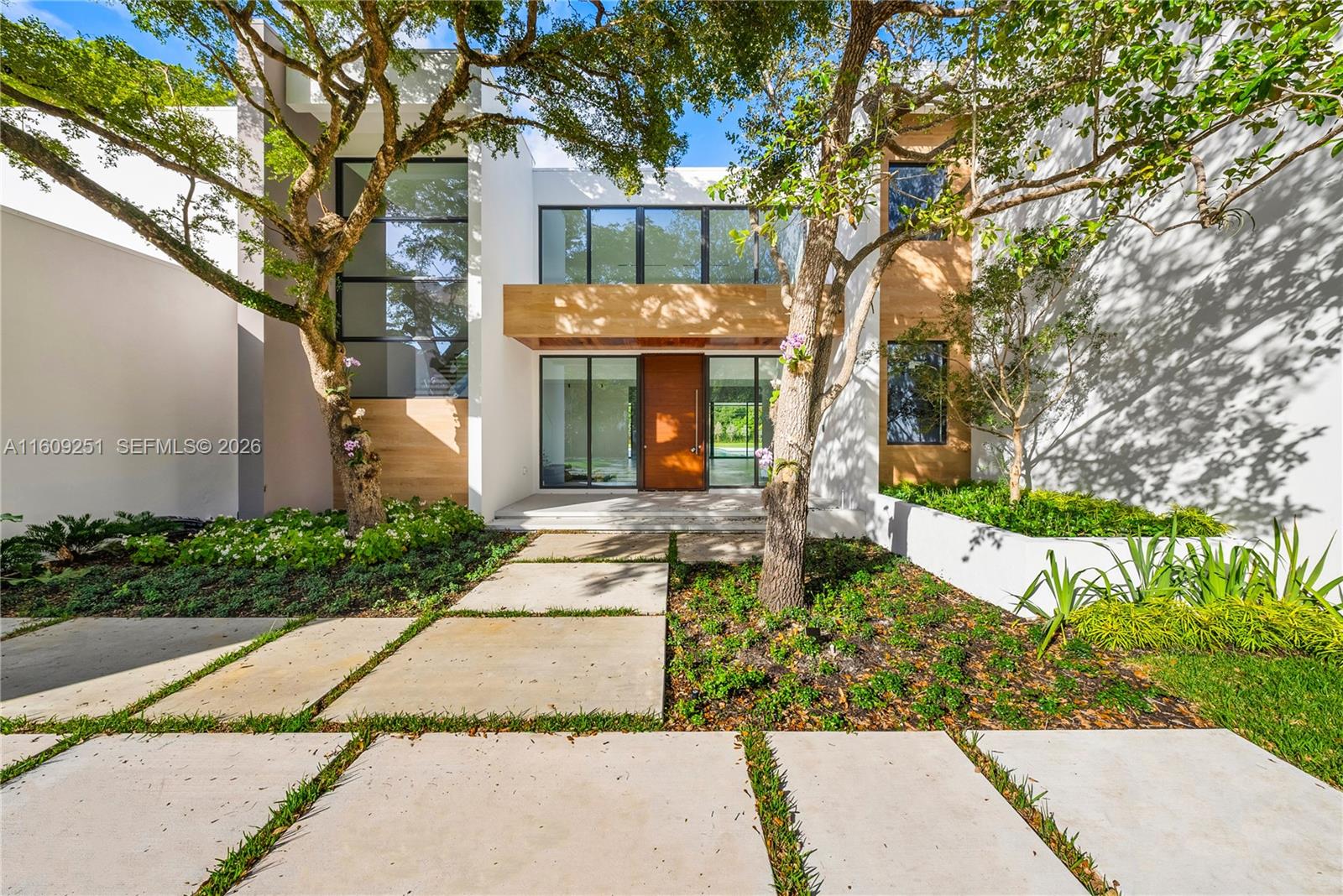 A modern two-story house features a wooden front door, large windows, and concrete pavers — 6675 SW 96th St, Pinecrest FL 33156, PINECREST, FL