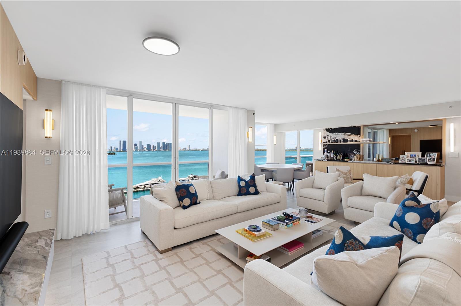 A bright living room features white sofas, a coffee table, and floor-to-ceiling windows overlooking water — 1800 Sunset Harbour Dr, Miami Beach FL 33139, MIAMI BEACH, FL