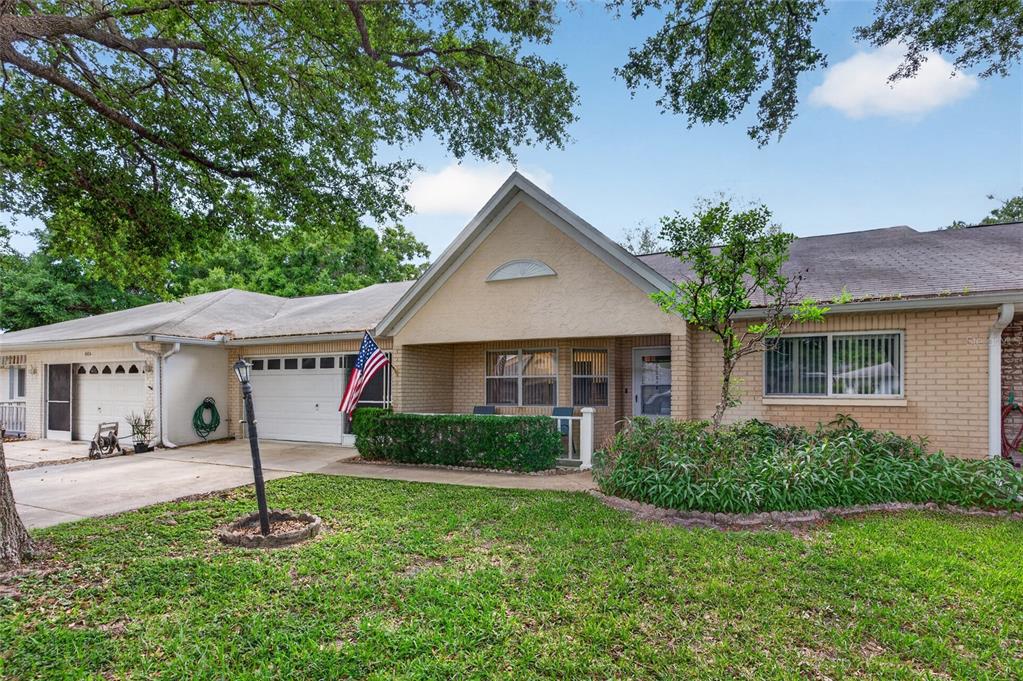 A single-story brick house with a front porch, a garage, and a large shade tree — 9060 SW 96TH LANE UNIT B, OCALA, FL