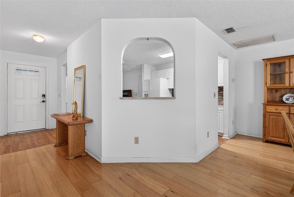 An interior view shows a white wall with an arched cutout overlooking a kitchen area — 9060 SW 96TH LANE UNIT B, OCALA, FL