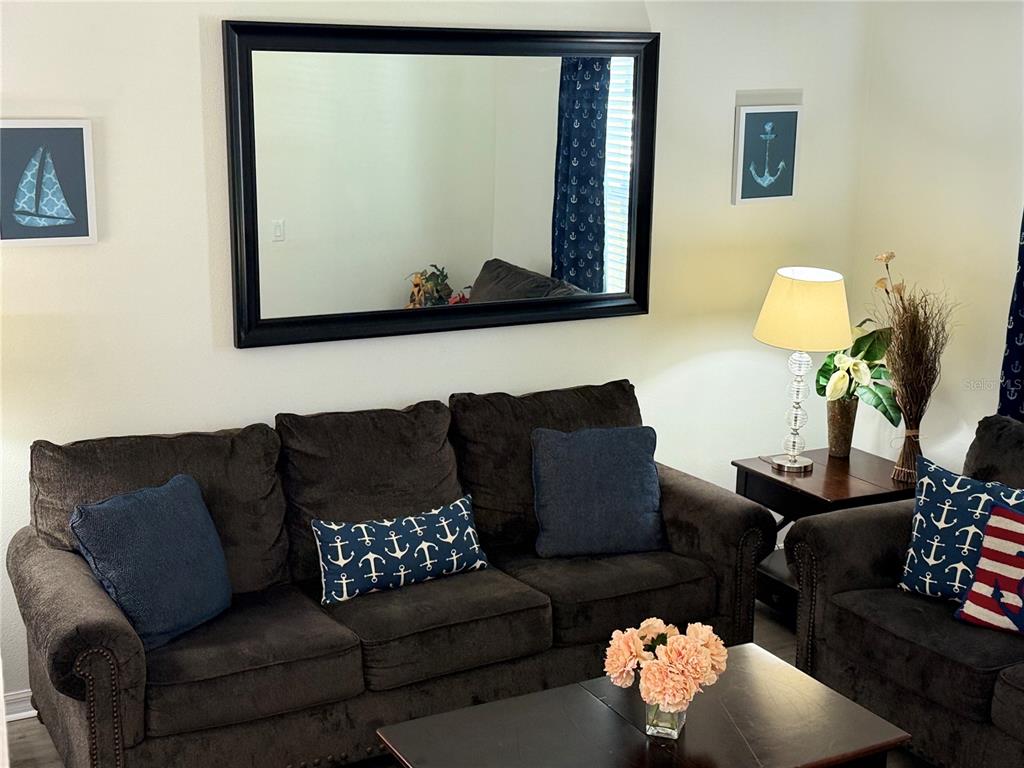 A living room features dark brown sofas, a large black-framed mirror, and nautical-themed decor — 2514 DHARMA CIRCLE, KISSIMMEE, FL