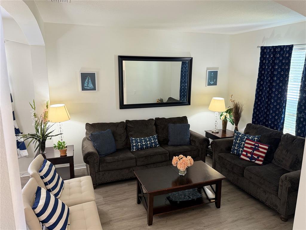 A living room features two dark sofas, a coffee table, and nautical-themed decor — 2514 DHARMA CIRCLE, KISSIMMEE, FL
