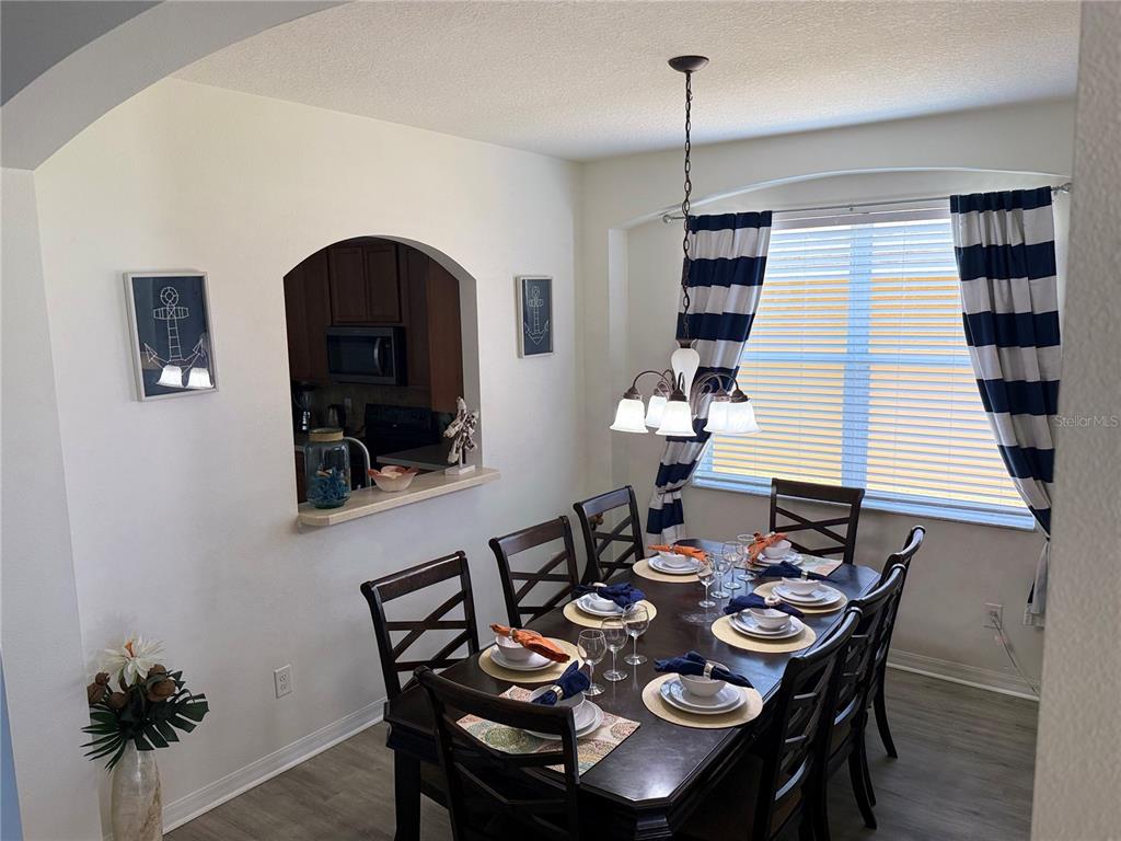 A dining room features a dark wood table, nautical decor, and striped curtains over a window — 2514 DHARMA CIRCLE, KISSIMMEE, FL