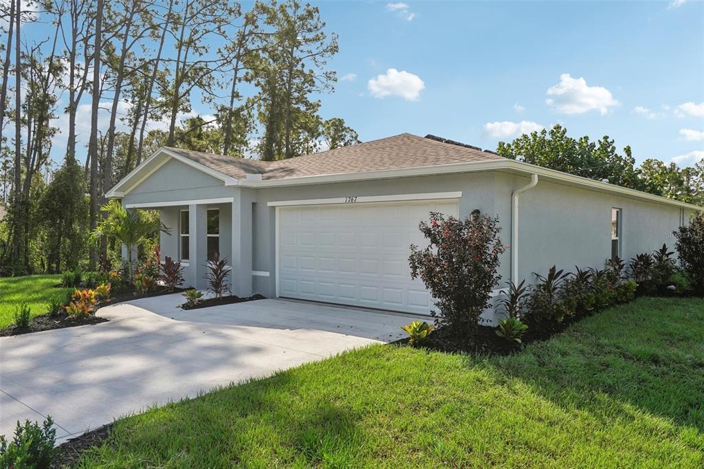A single-story house with a gray exterior, a two-car garage, and a landscaped front yard — 1026 AMBLESIDE DRIVE, HAINES CITY, FL