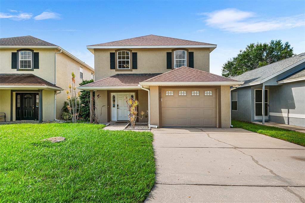 A two-story suburban house with a tan exterior, a single-car garage, and a front lawn — 2101 HATTERAS POINT, LAKELAND, FL