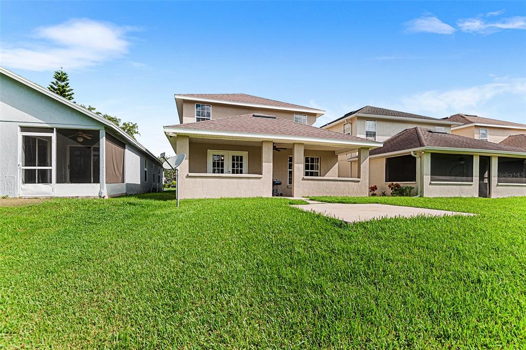 The exterior rear view of a two-story house with a covered patio and lawn — 2101 HATTERAS POINT, LAKELAND, FL