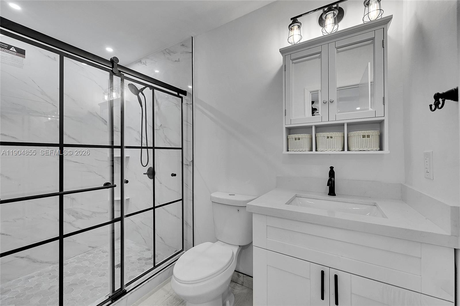 A modern bathroom features a glass-enclosed shower, a white vanity, and a toilet — 4603 King Palm Dr, Tamarac FL 33319, TAMARAC, FL