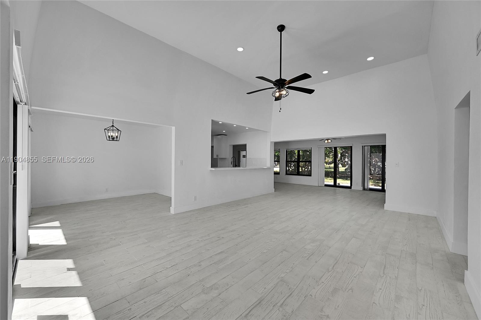 A bright, open-concept living area features vaulted ceilings, white walls, and light wood-look flooring — 4603 King Palm Dr, Tamarac FL 33319, TAMARAC, FL