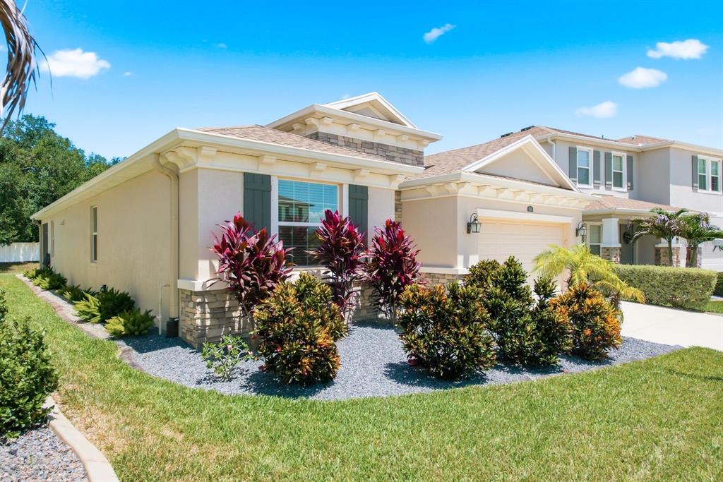 A single-story house with a beige stucco exterior, stone accents, and a landscaped front yard — 8036 PRAISE DRIVE, TAMPA, FL
