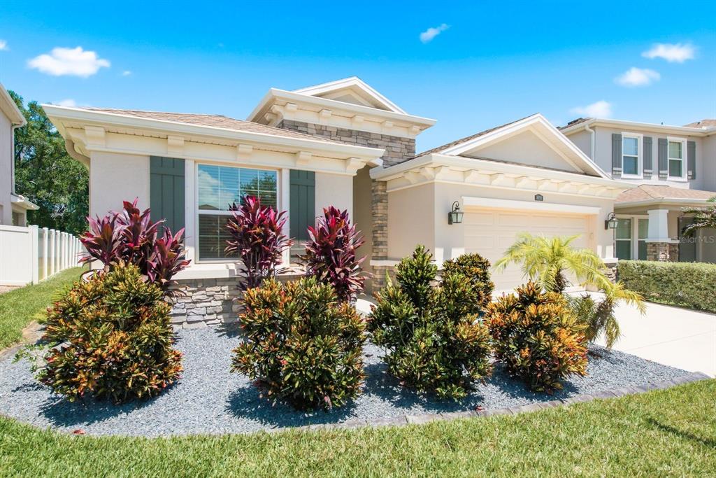 A single-story house with a beige stucco exterior, stone accents, and a landscaped front yard — 8036 PRAISE DRIVE, TAMPA, FL