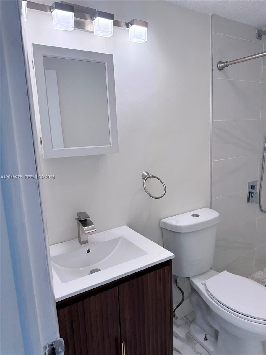 A modern bathroom features a white vanity, a medicine cabinet, and a tiled shower area — 453 SW 2nd St # 306C, Miami FL 33130, MIAMI, FL