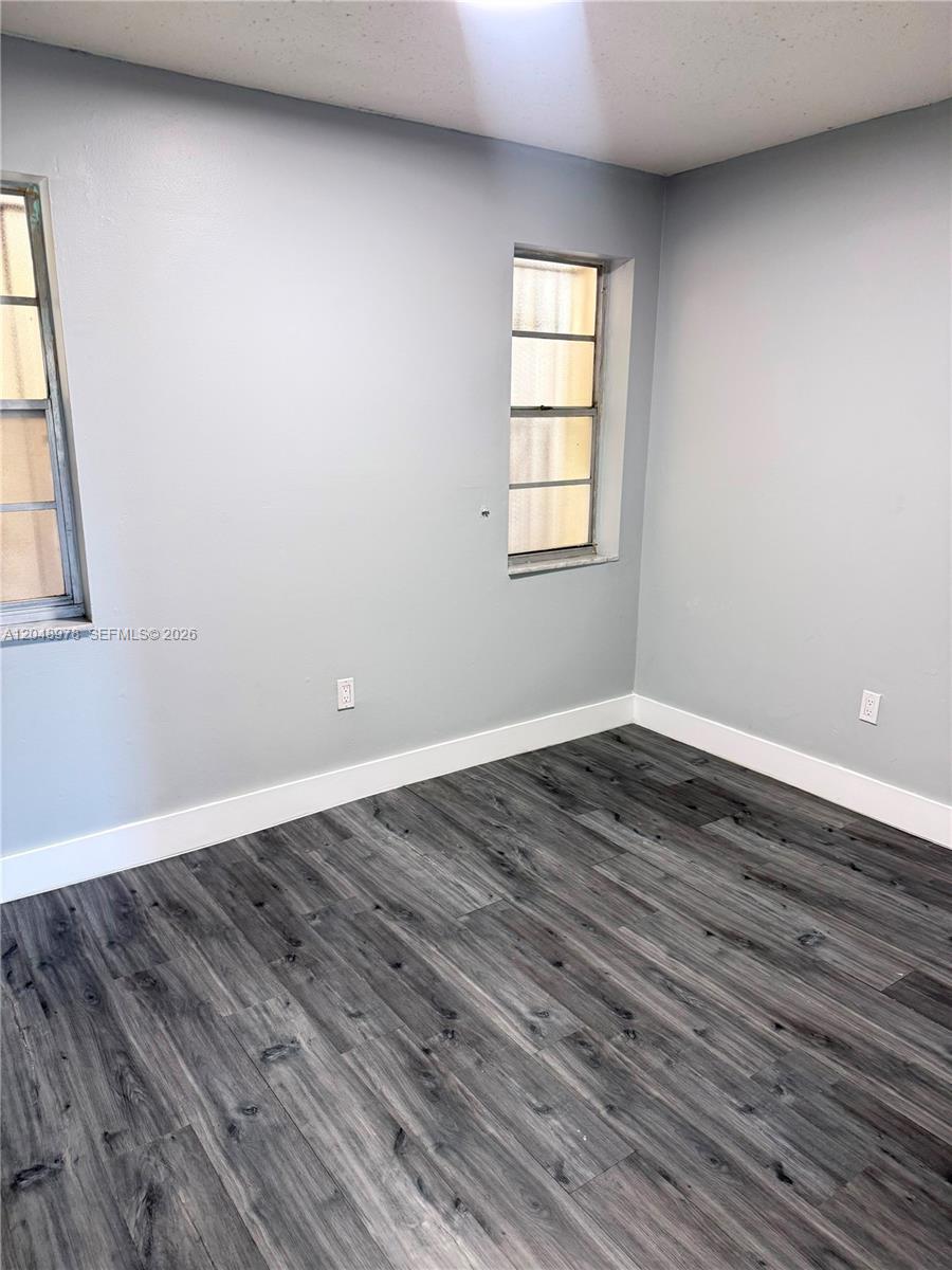An empty room features light gray walls, white baseboards, and dark wood-look laminate flooring — 453 SW 2nd St # 306C, Miami FL 33130, MIAMI, FL
