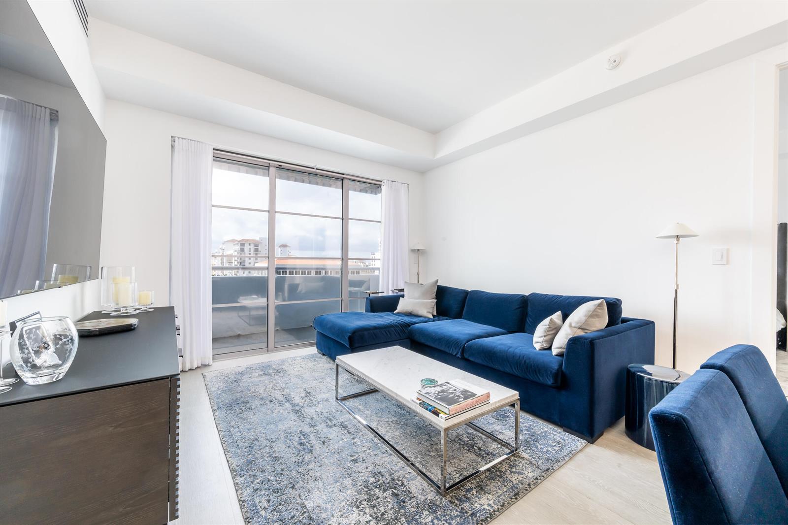 A living room features a blue sectional sofa, a marble coffee table, and a balcony view — 155 E Boca Raton Road # 818, Boca Raton FL 33432, BOCA RATON, FL