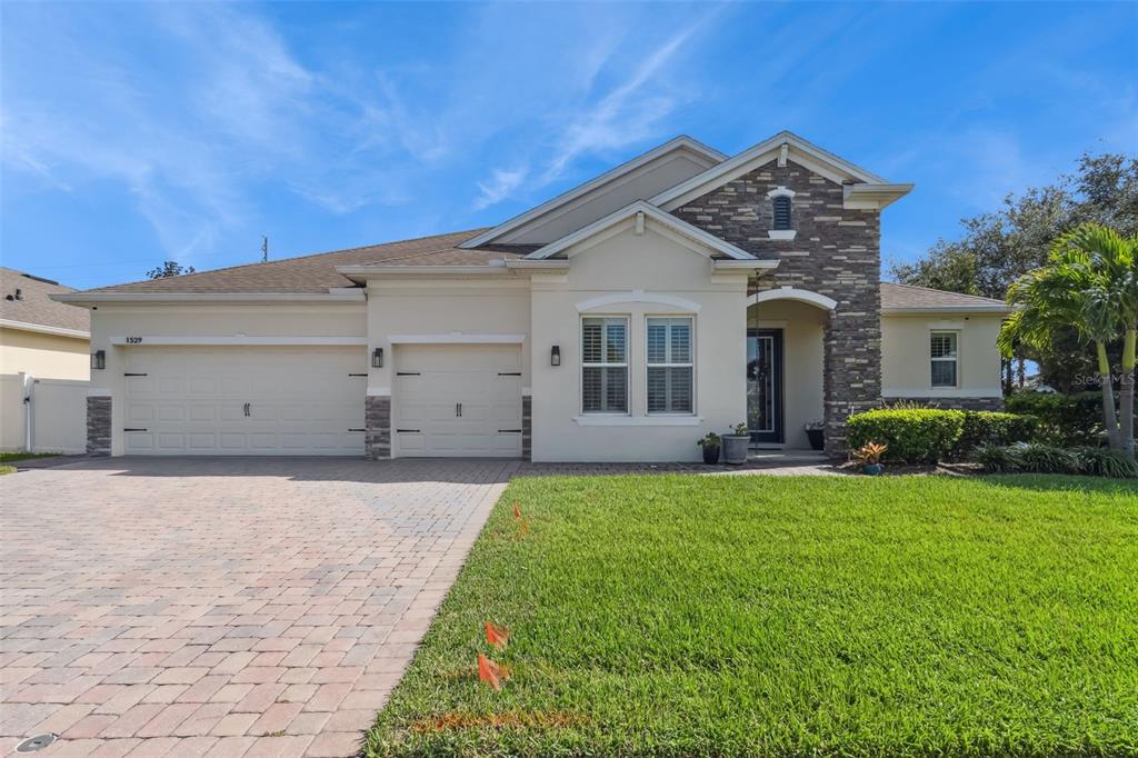 A single-story house with a stone-accented facade, a two-car garage, and a paved driveway — 1529 ALLIGATOR STREET, ST CLOUD, FL