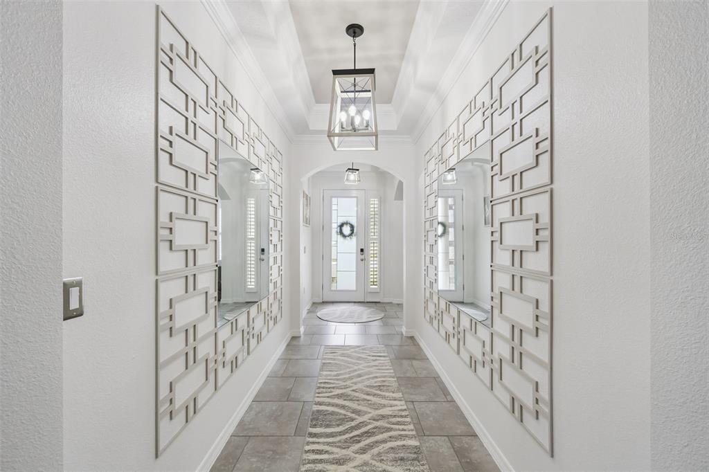 A bright hallway features tiled floors, a runner rug, and large geometric wall mirrors — 1529 ALLIGATOR STREET, ST CLOUD, FL