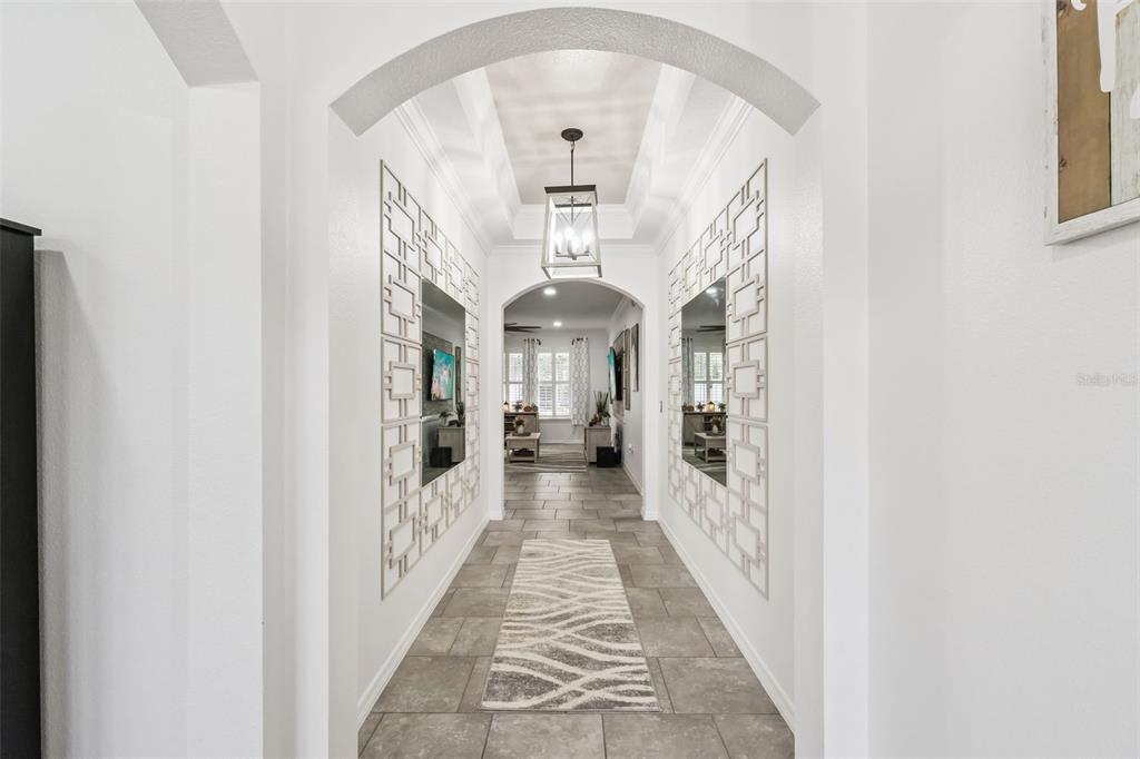 A hallway features arched entryways, tiled floors, a runner rug, and decorative wall mirrors — 1529 ALLIGATOR STREET, ST CLOUD, FL