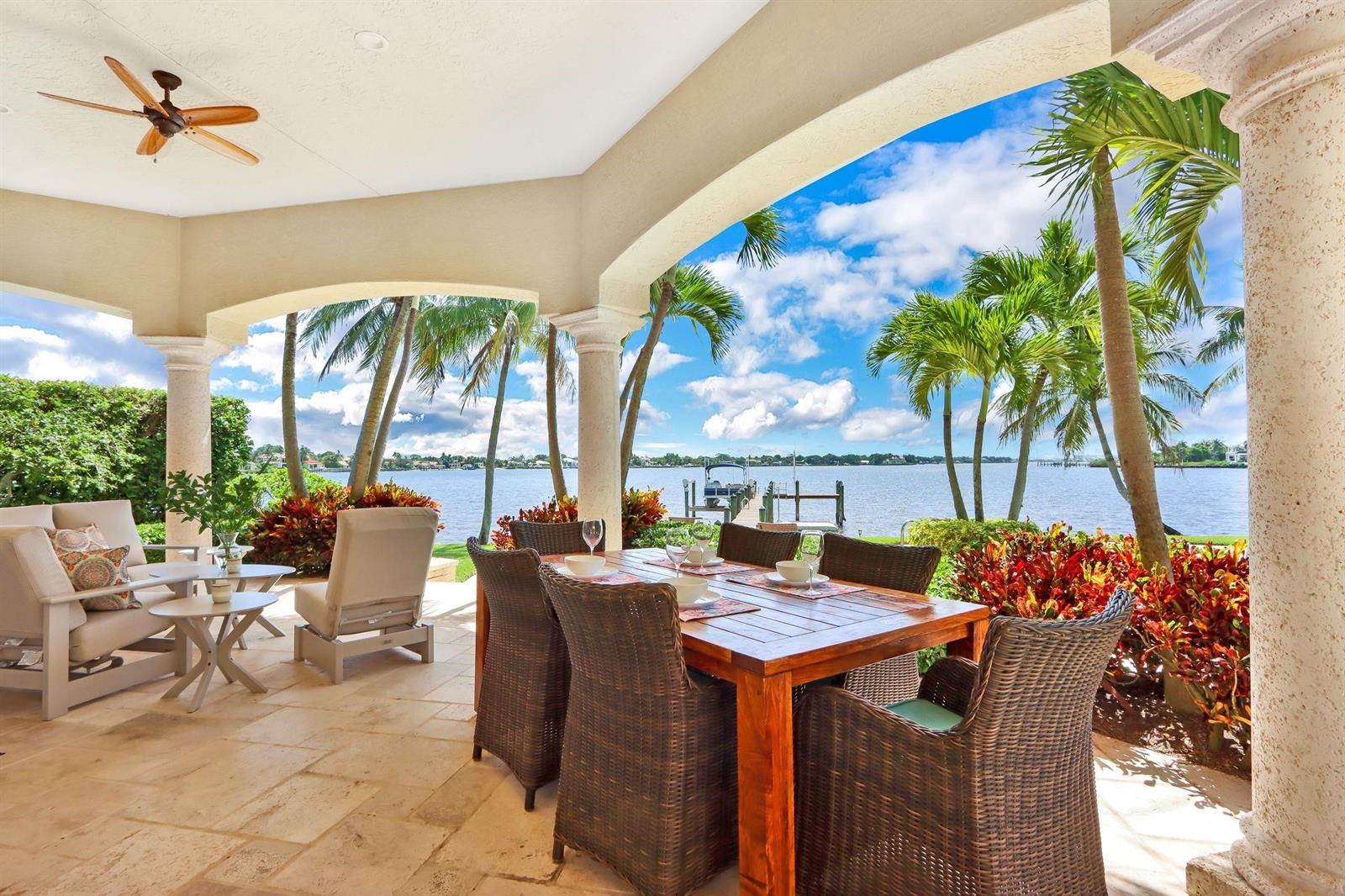 A covered patio features a dining set, lounge chairs, and a view of the water — 19022 Loxahatchee River Road, Jupiter FL 33458, JUPITER, FL