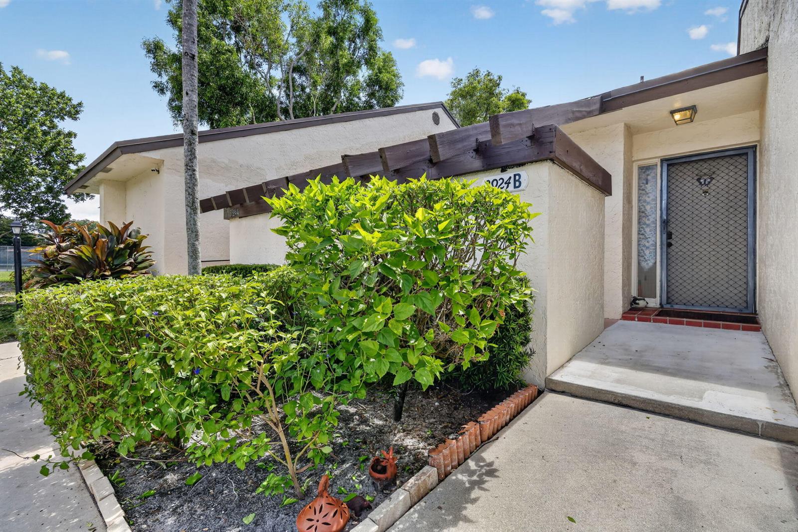 A view of a residential building exterior with a walkway, landscaping, and a front door — 3924 San Anselmo Drive # B, Lake Worth FL 33467, LAKE WORTH, FL