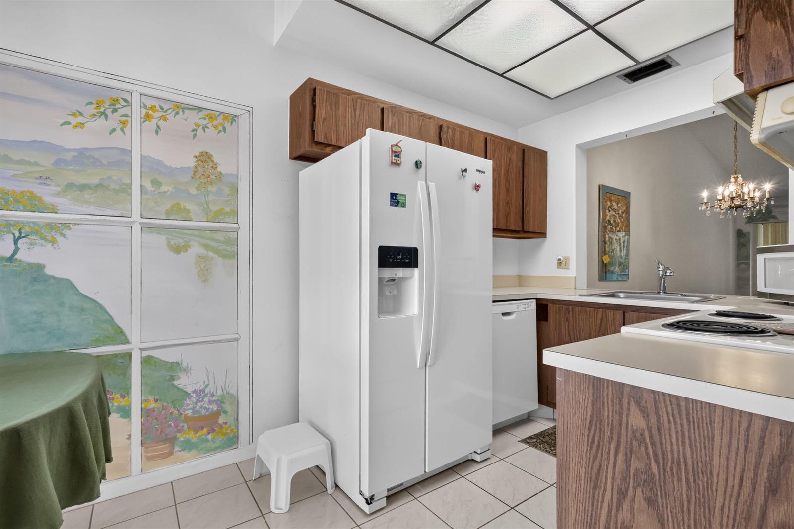 A kitchen features white appliances, wood cabinets, tile flooring, and a painted window mural — 3924 San Anselmo Drive # B, Lake Worth FL 33467, LAKE WORTH, FL