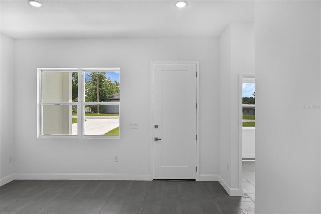 A room with white walls, dark tile flooring, a window, and a white door — 20563 SW RAINBOW LAKES BOULEVARD, DUNNELLON, FL