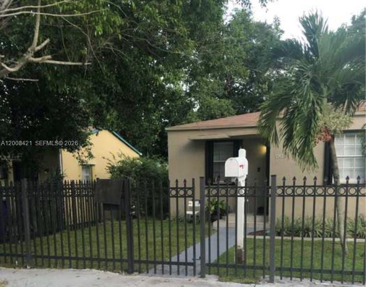 A beige house with a black metal fence and a palm tree in the front yard — 1342 NW 42nd St, Miami FL 33142, MIAMI, FL