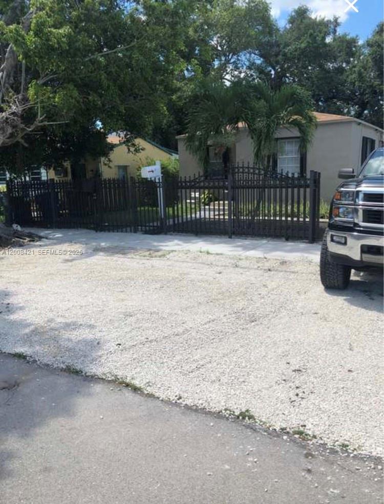A gravel driveway leads to a single-story house enclosed by a black metal fence — 1342 NW 42nd St, Miami FL 33142, MIAMI, FL