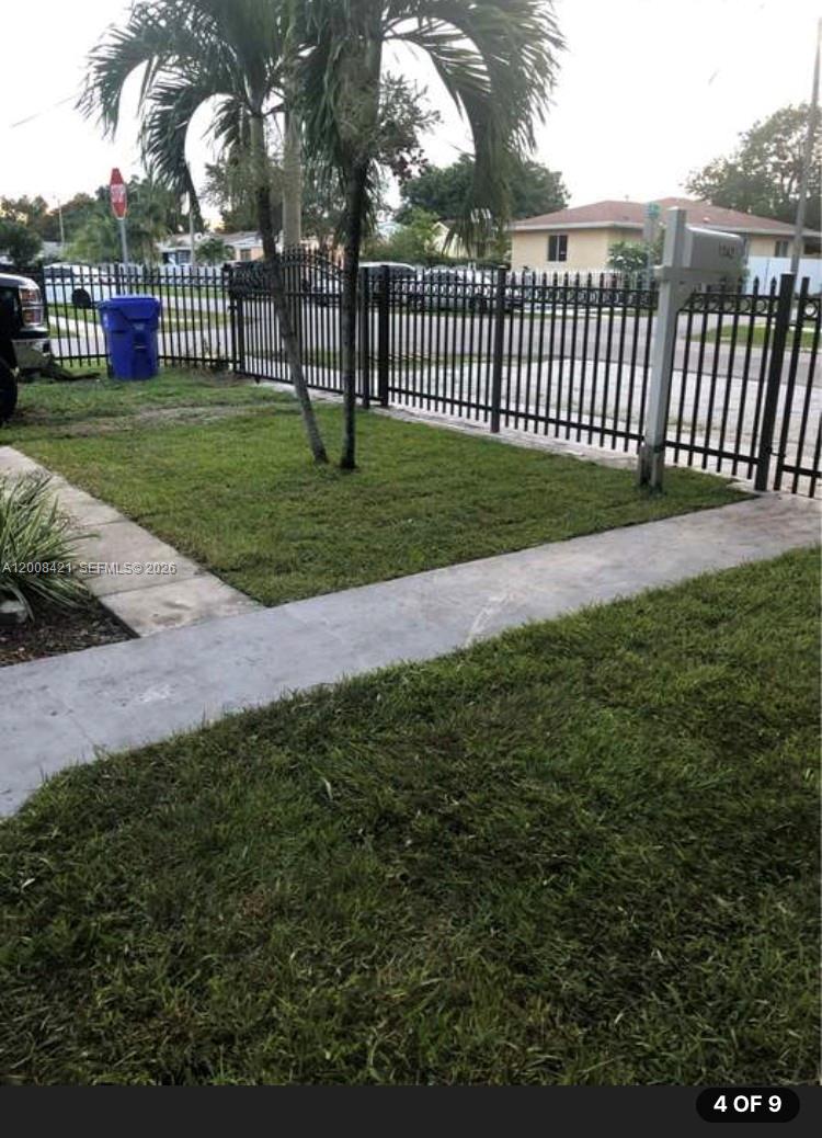 A fenced front yard features a concrete walkway, a palm tree, and a blue bin — 1342 NW 42nd St, Miami FL 33142, MIAMI, FL