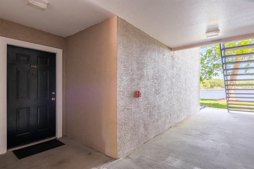 A black front door labeled 110 sits next to a textured wall and outdoor stairs — 4209 WOODSTORKS WALK WAY UNIT 1110, LUTZ, FL