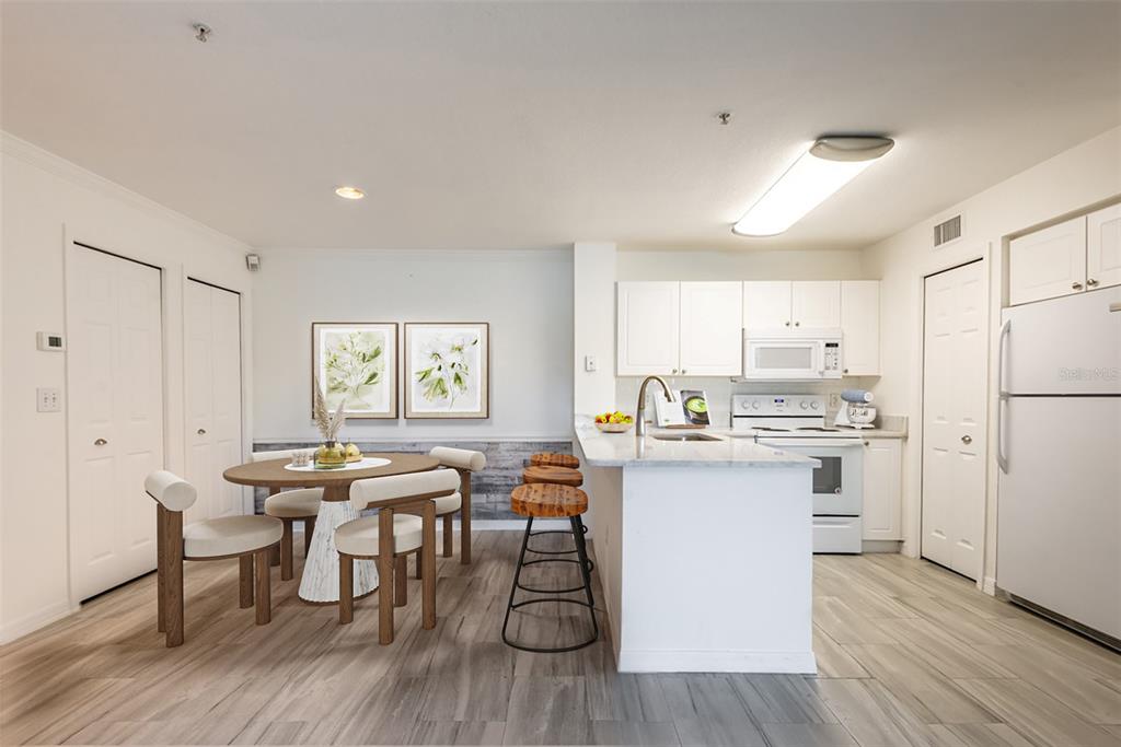 A kitchen and dining area with white cabinets, a breakfast bar, and wood-look flooring — 4209 WOODSTORKS WALK WAY UNIT 1110, LUTZ, FL