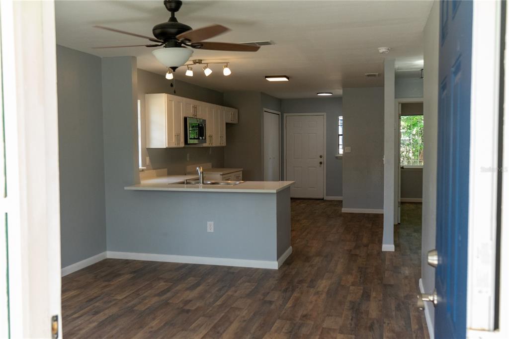 An open-concept kitchen with white cabinets and a breakfast bar overlooks a living area — 1307 RAILROAD AVENUE, SANFORD, FL