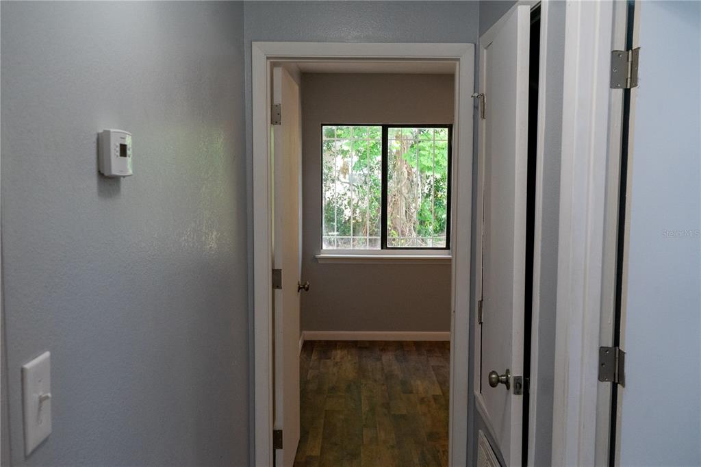 A hallway leads into a room with wood-look flooring and a window with security bars — 1307 RAILROAD AVENUE, SANFORD, FL