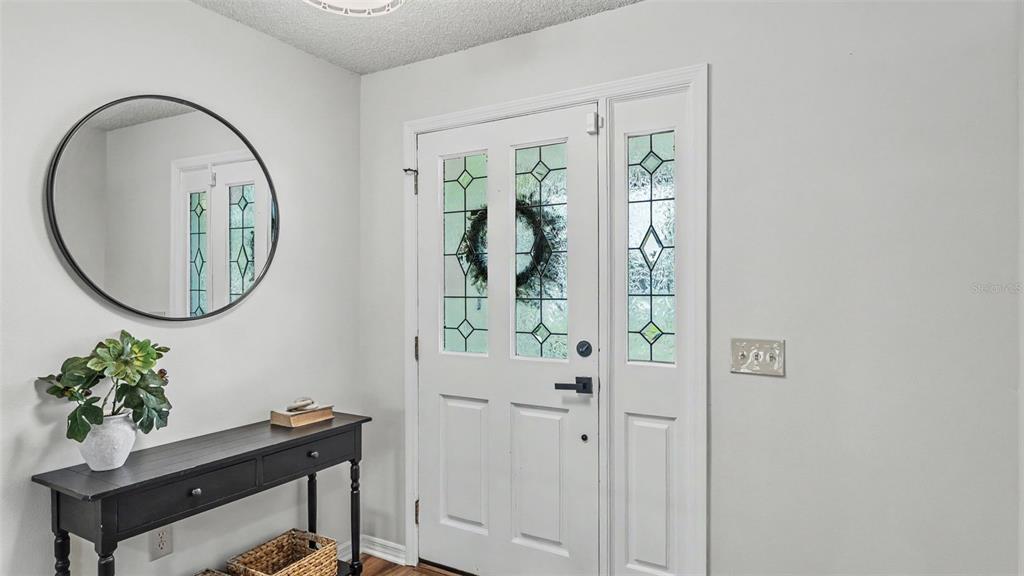 An entryway features a white front door with glass panels, a round mirror, and a console — 4765 HIGHLANDS PLACE CIRCLE, LAKELAND, FL