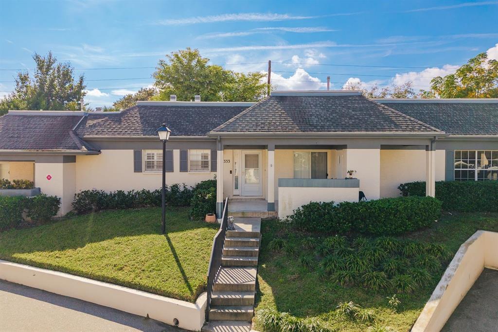 A single-story residential building features a front porch, stairs, and a grassy lawn — 1333 N MCMULLEN BOOTH ROAD UNIT 1333, CLEARWATER, FL