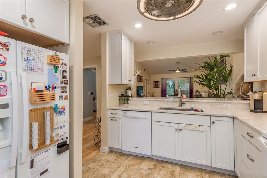 A kitchen features white cabinets, a dishwasher, a sink, and a view into the living area — 1333 N MCMULLEN BOOTH ROAD UNIT 1333, CLEARWATER, FL