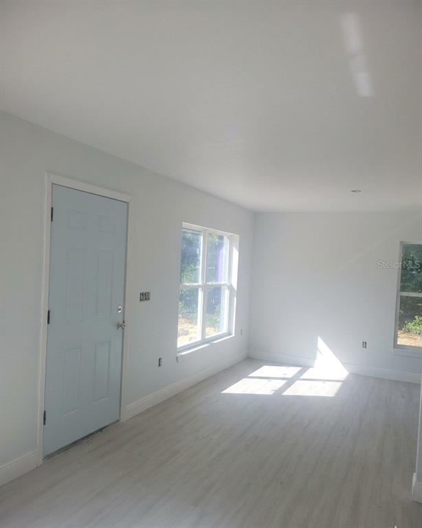 A bright room features light-colored wood-look flooring, white walls, and a light blue door — 338 2ND WAY, INTERLACHEN, FL