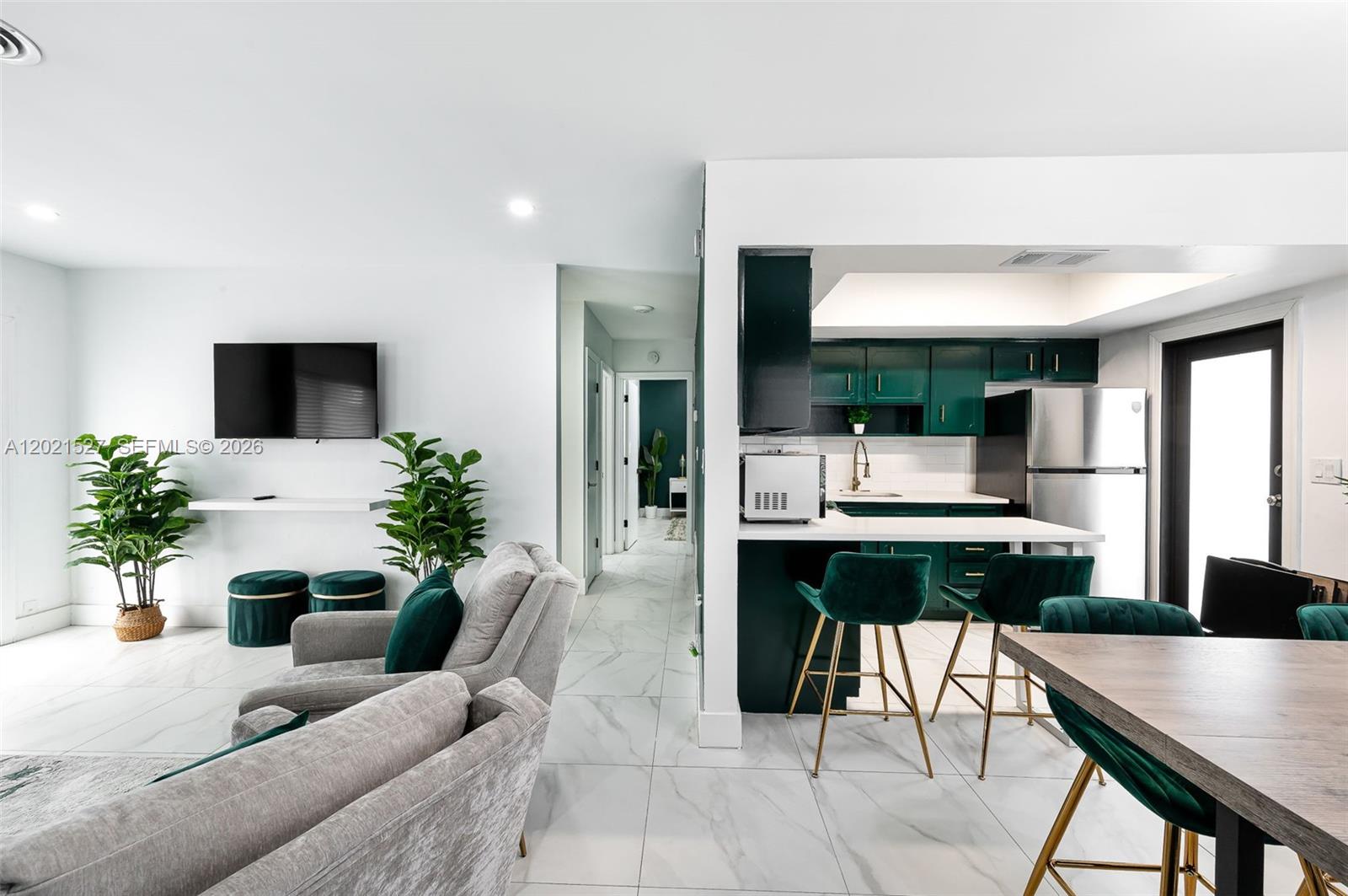 A living room with gray furniture and a kitchen with green cabinets and gold stools — 329 SE 12th Ave # 1, Pompano Beach FL 33060, POMPANO BEACH, FL