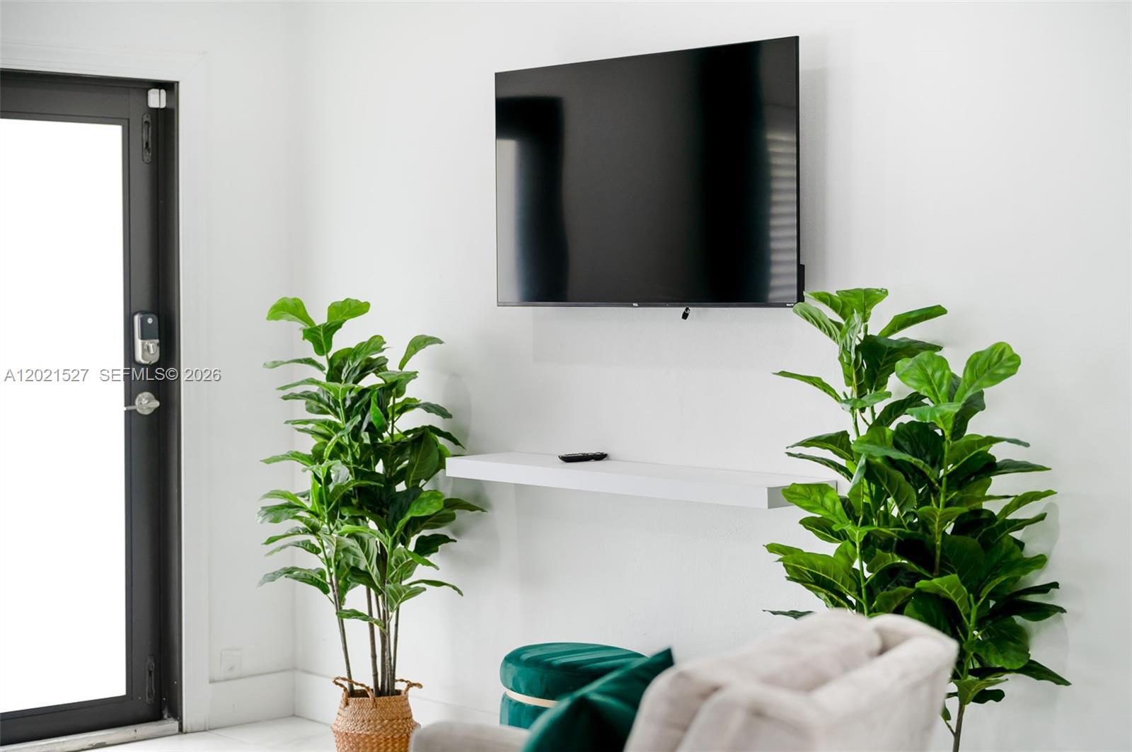 A wall-mounted television hangs above a floating shelf between two potted plants — 329 SE 12th Ave # 1, Pompano Beach FL 33060, POMPANO BEACH, FL