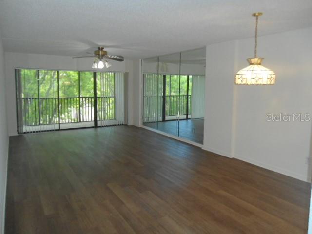 An open living area features wood-look flooring, a ceiling fan, and a mirrored wall — 2800 COVE CAY DRIVE UNIT 4D, CLEARWATER, FL