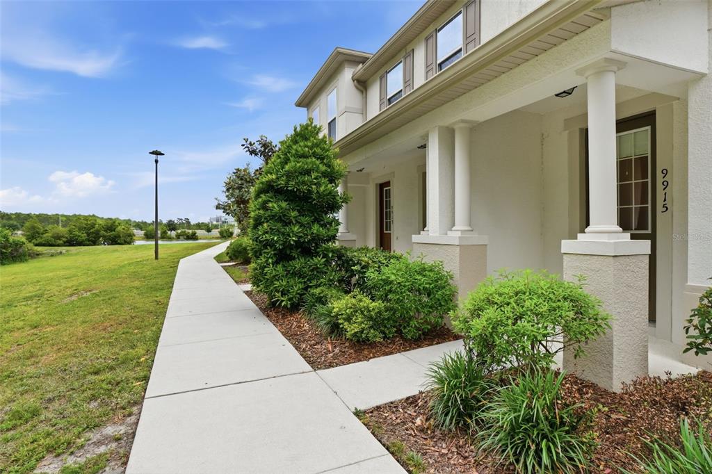 A sidewalk leads along the front of a two-story building with a covered porch — 9915 HIGHLAND SKY ALLEY, ORLANDO, FL