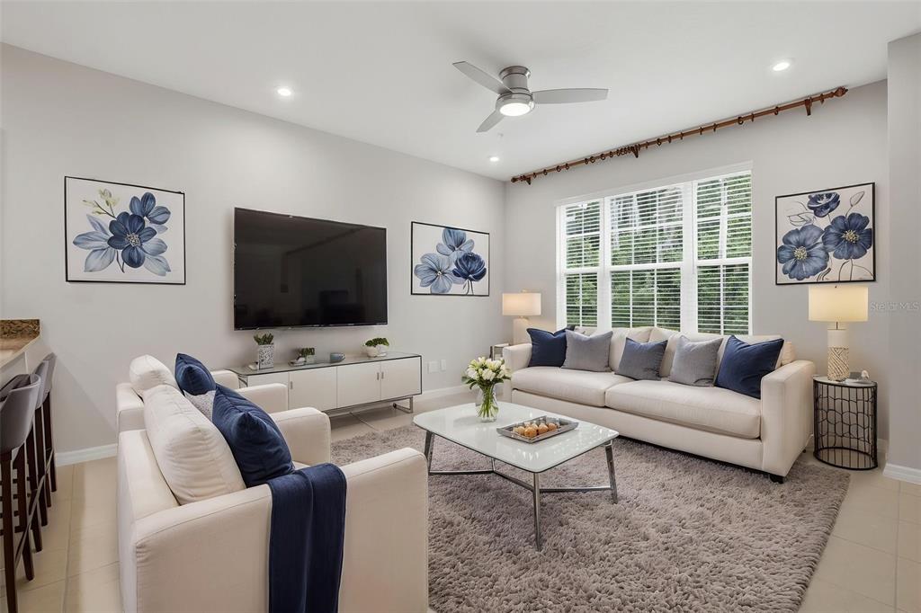 A living room features a white sofa, matching armchair, glass coffee table, and wall-mounted television — 9915 HIGHLAND SKY ALLEY, ORLANDO, FL