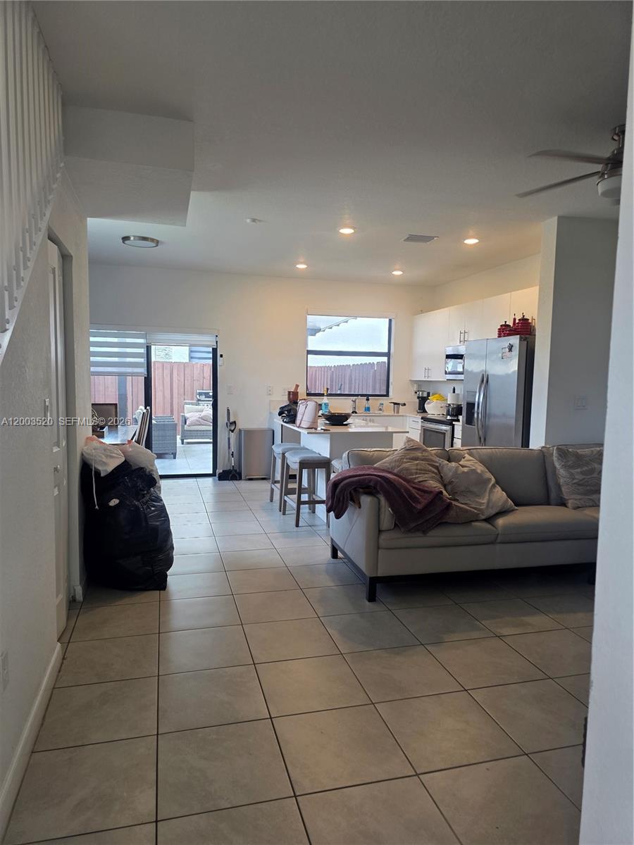 An open-concept kitchen and living area features tile flooring, a breakfast bar, and sliding doors — 23231 SW 129th Path # 0, Homestead FL 33170, HOMESTEAD, FL