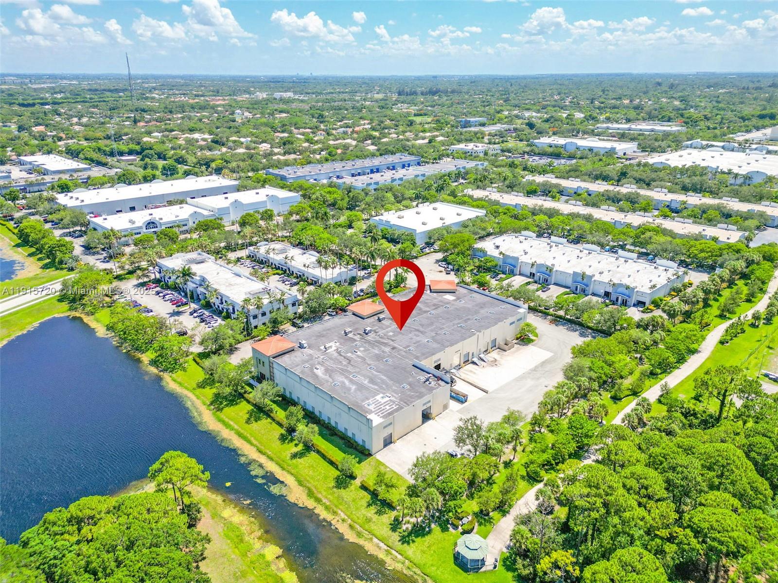 An aerial view shows a large industrial warehouse building situated next to a canal — 6850 Lyons Technology Cir, Coconut Creek FL 33073, COCONUT CREEK, FL